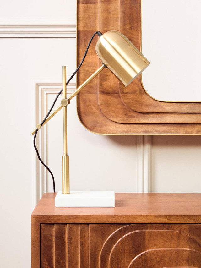 Carved mango wood wall mirror styled with a lamp in a bright, contemporary interior