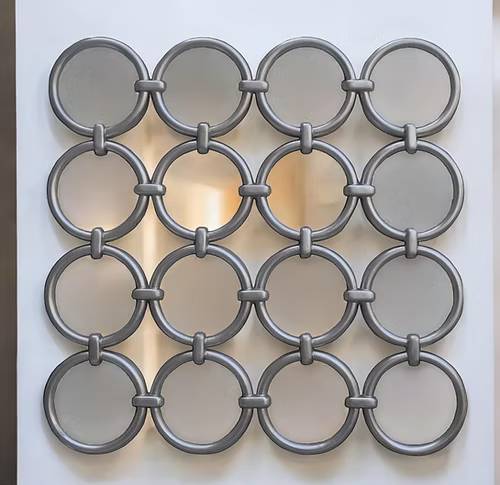 Decorative metal wall mirror with circular patterns on a white background