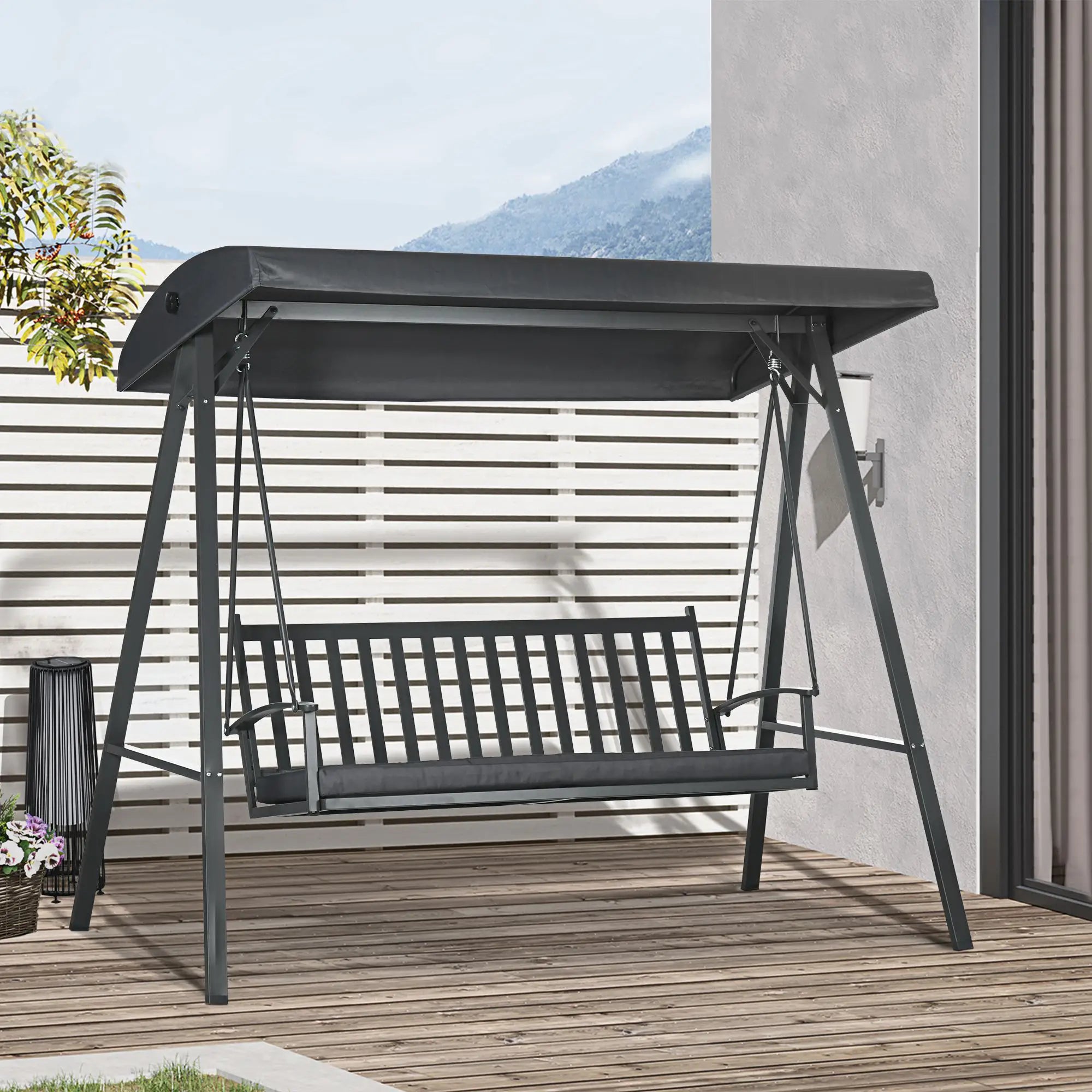 Black metal swing with canopy on a wooden deck