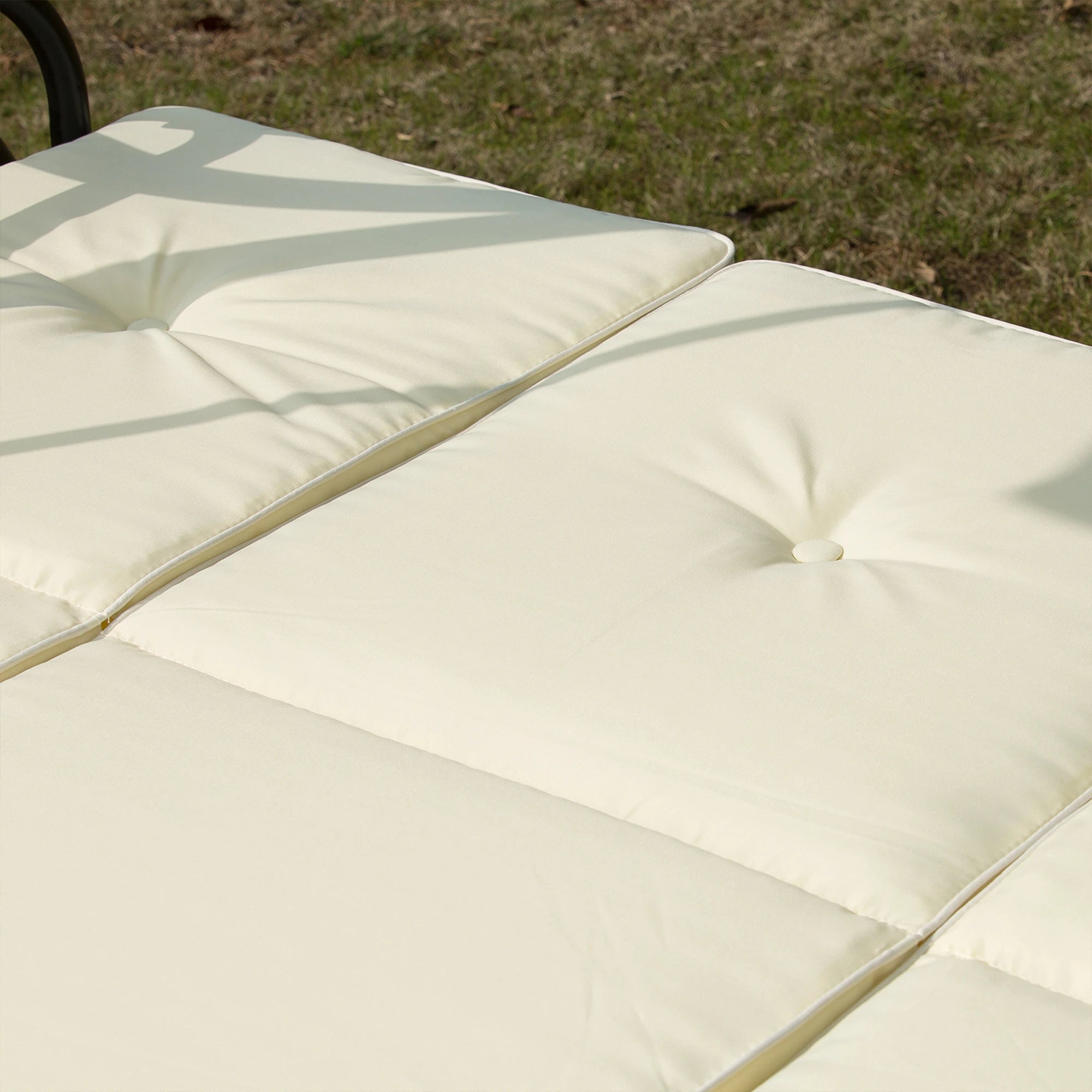 Close-up of beige outdoor cushions on a chair with grass in the background