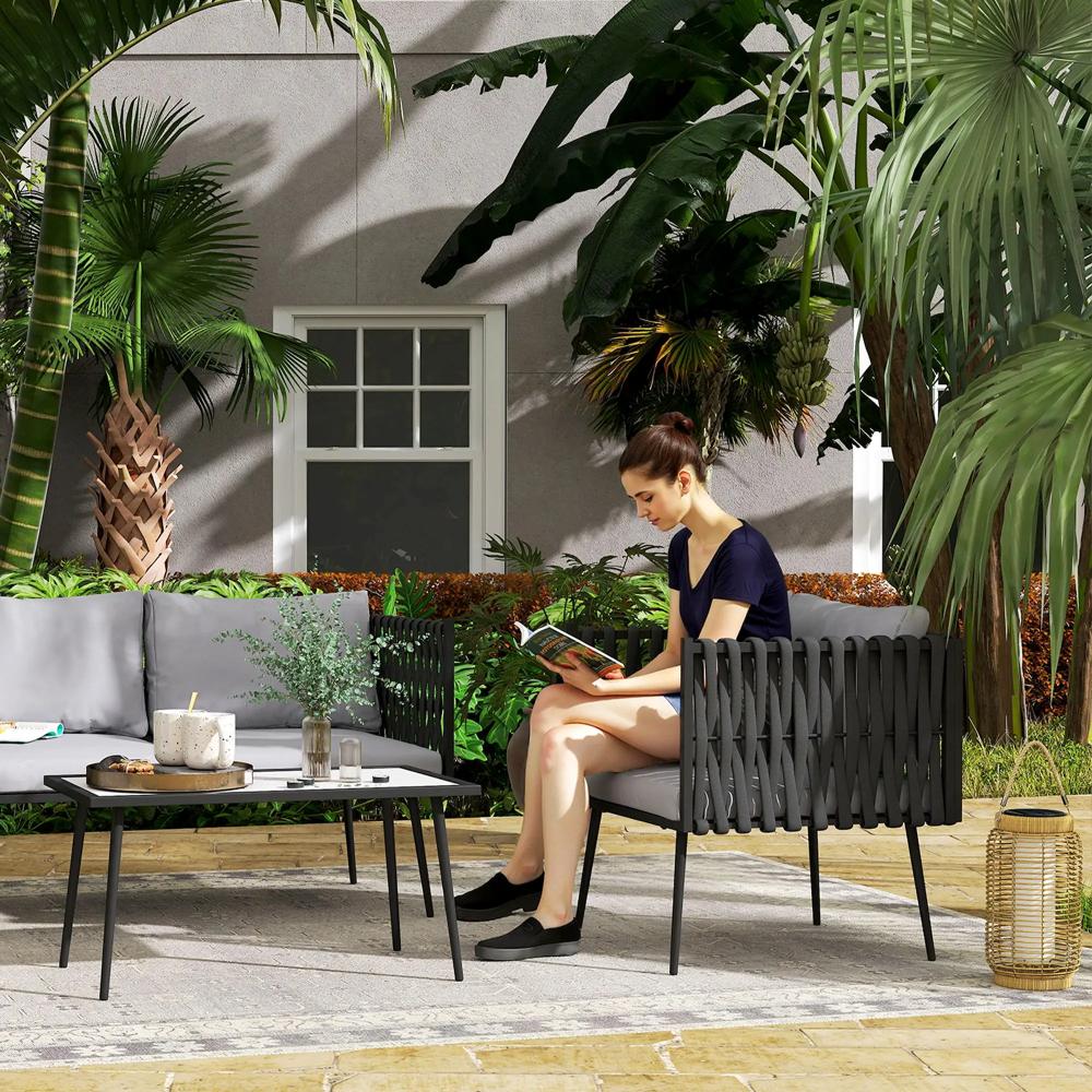 Woman sitting on a modern outdoor chair reading a book in a garden setting with plants and furniture.