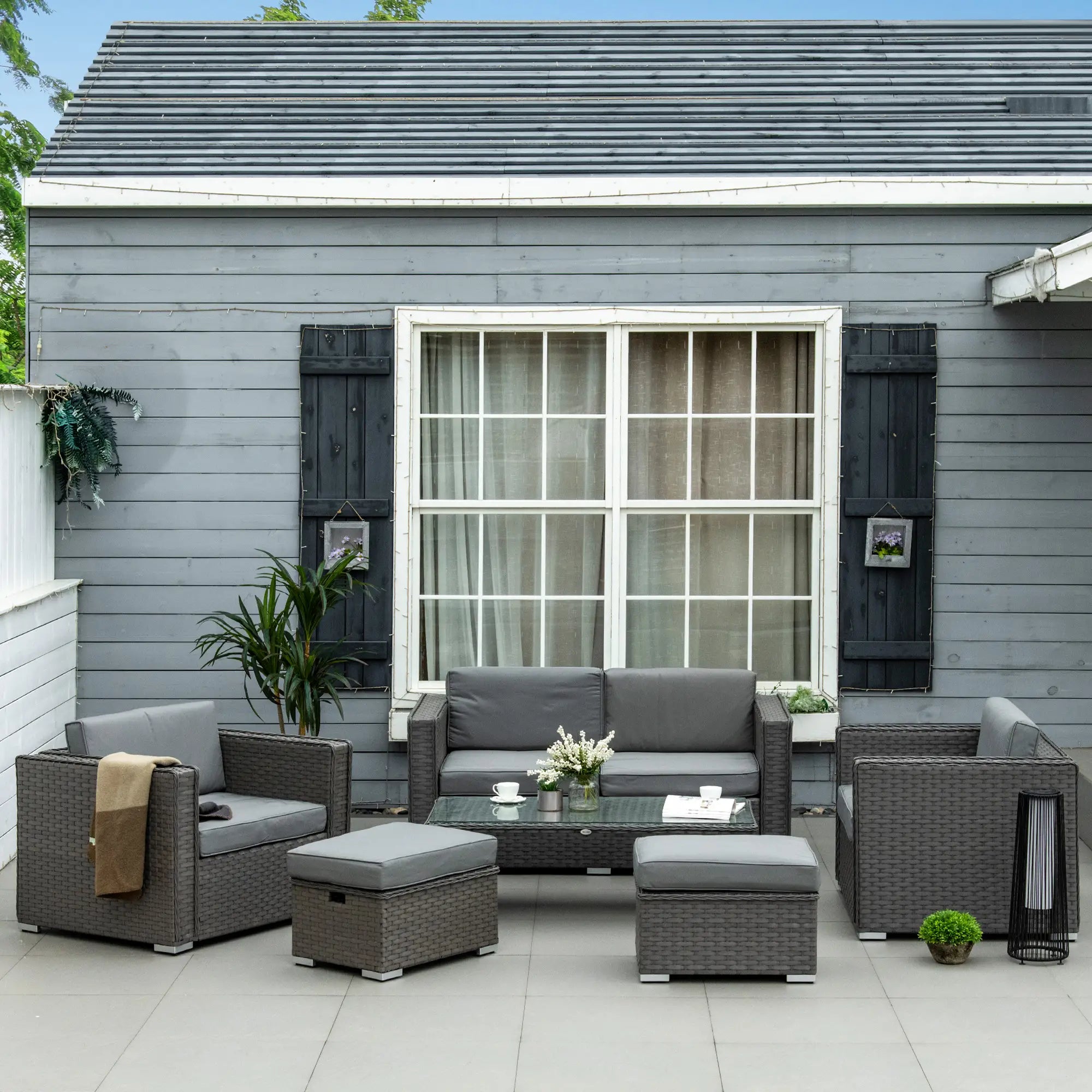 Outdoor patio set with gray furniture in front of a gray house.