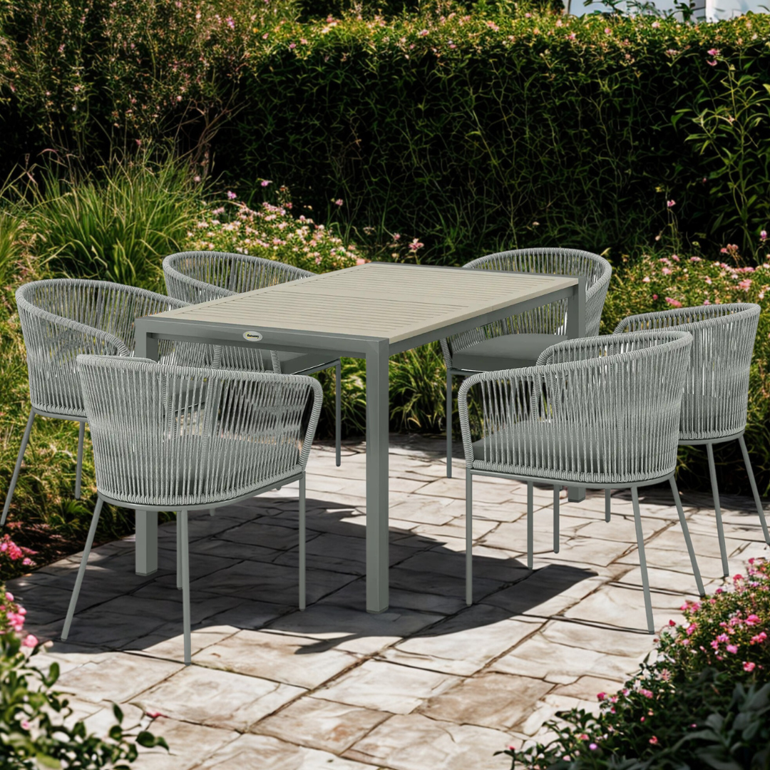 Outdoor patio set with a table and chairs on a stone patio surrounded by greenery.