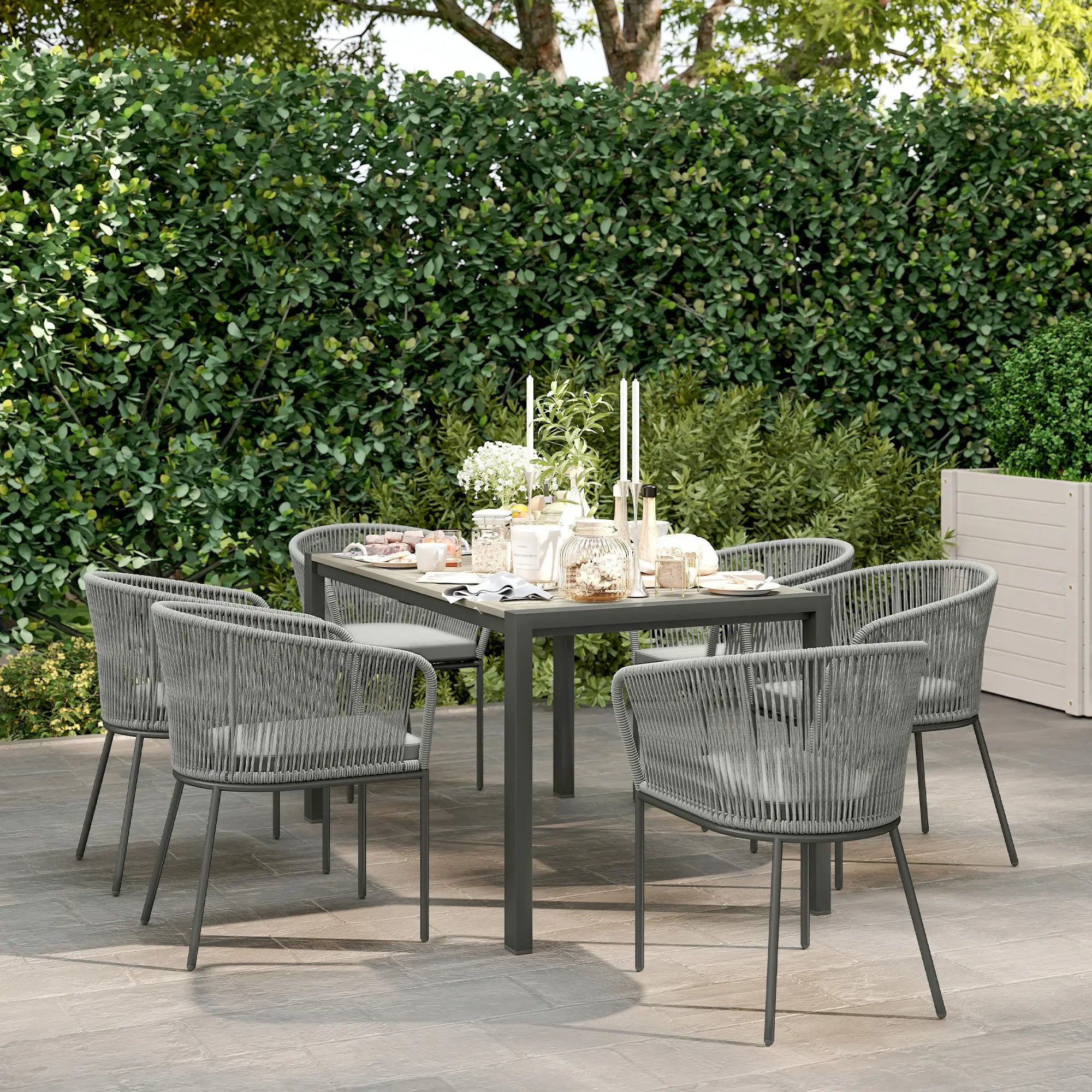 Outdoor dining setup with a table and chairs on a wooden deck, surrounded by greenery.