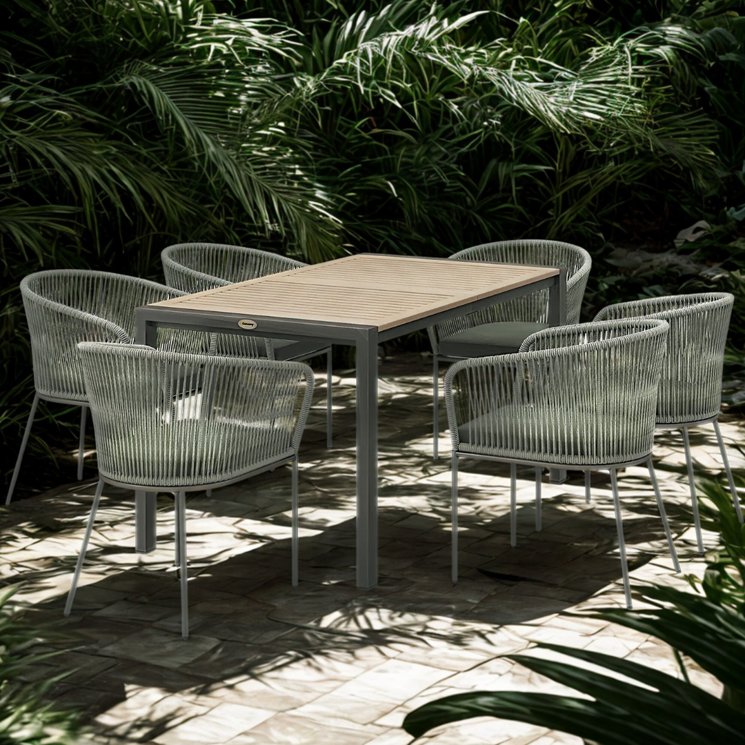 Outdoor dining set with a table and six chairs on a patio surrounded by greenery.