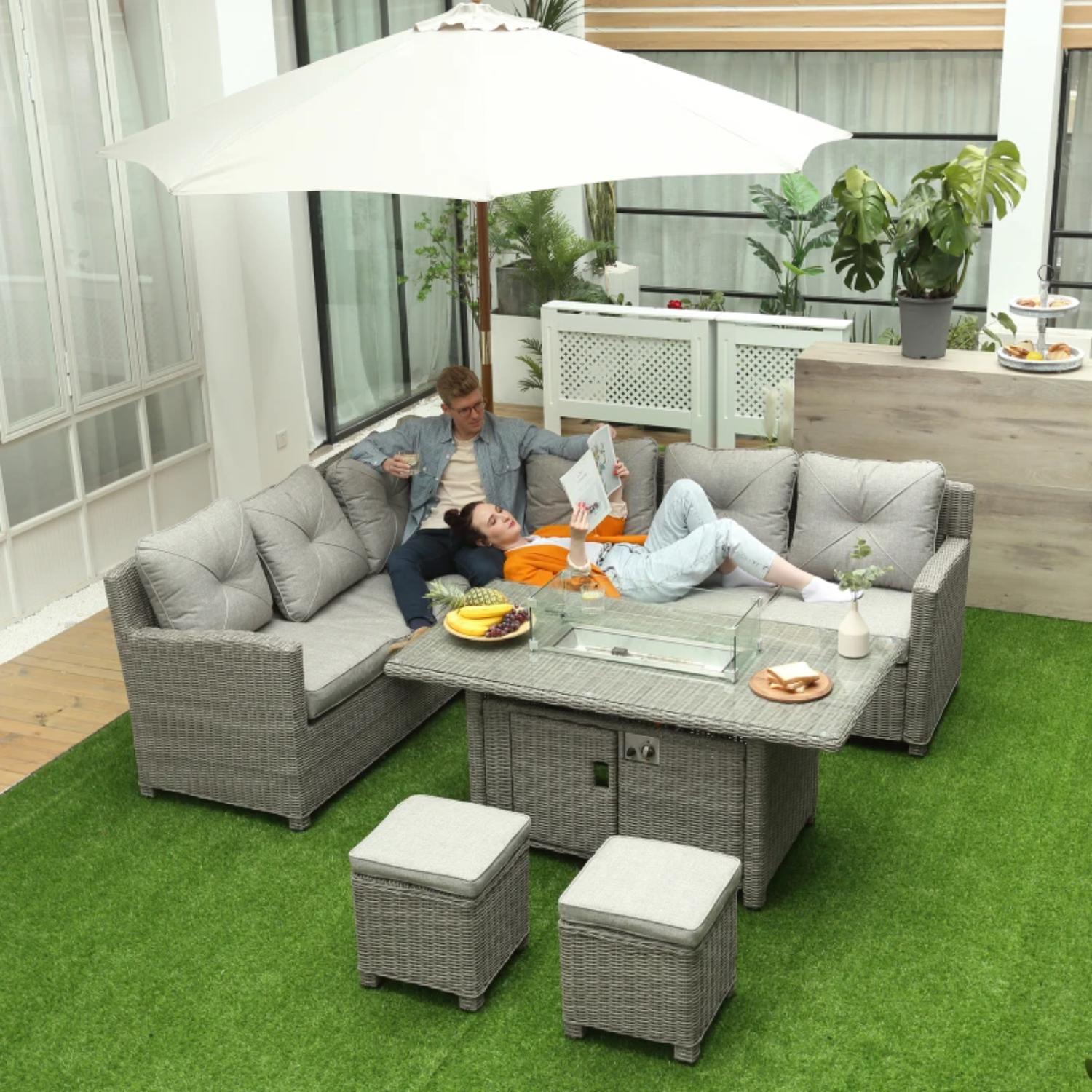 Outdoor patio set with gray cushions, table, and ottomans on a green lawn.