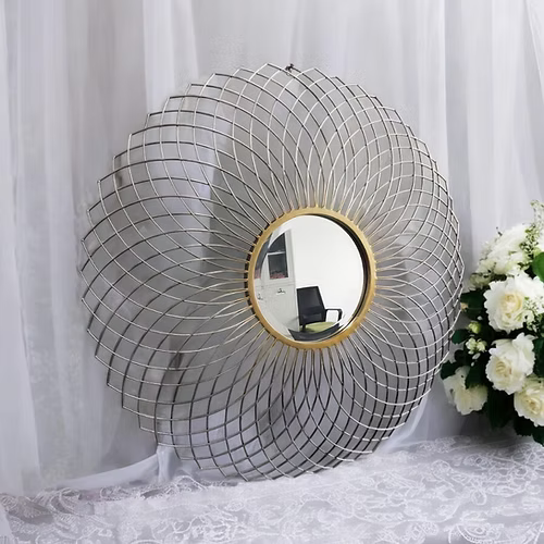 Decorative round mirror with wireframe design on a white lace tablecloth with flowers.