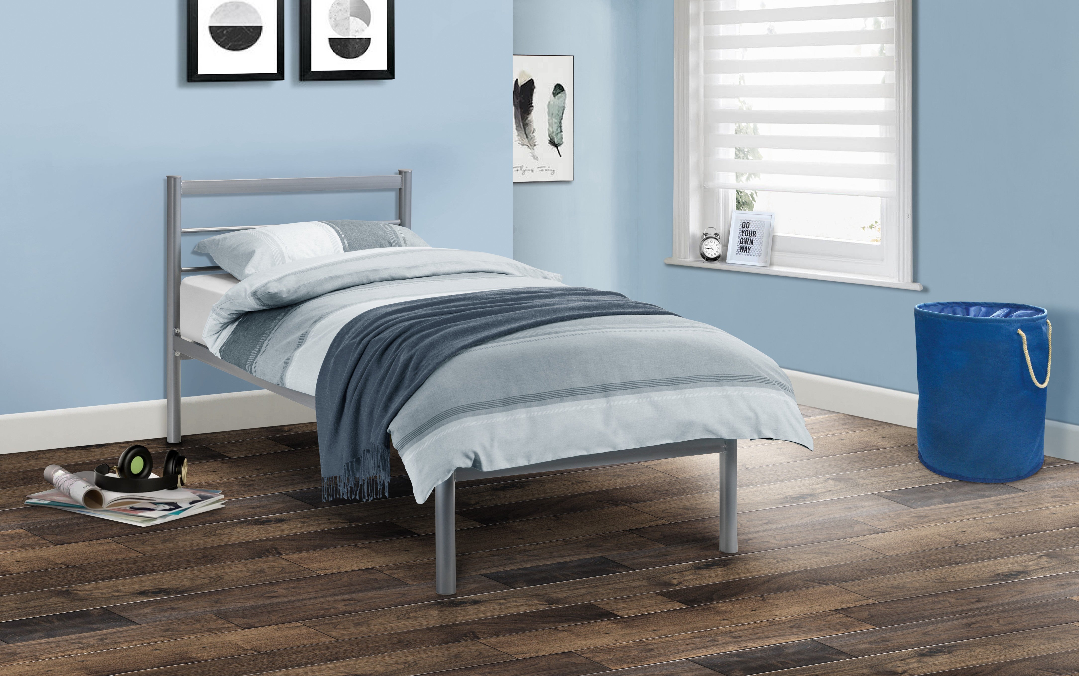 Bedroom with a metal bed frame, blue walls, and wooden flooring.