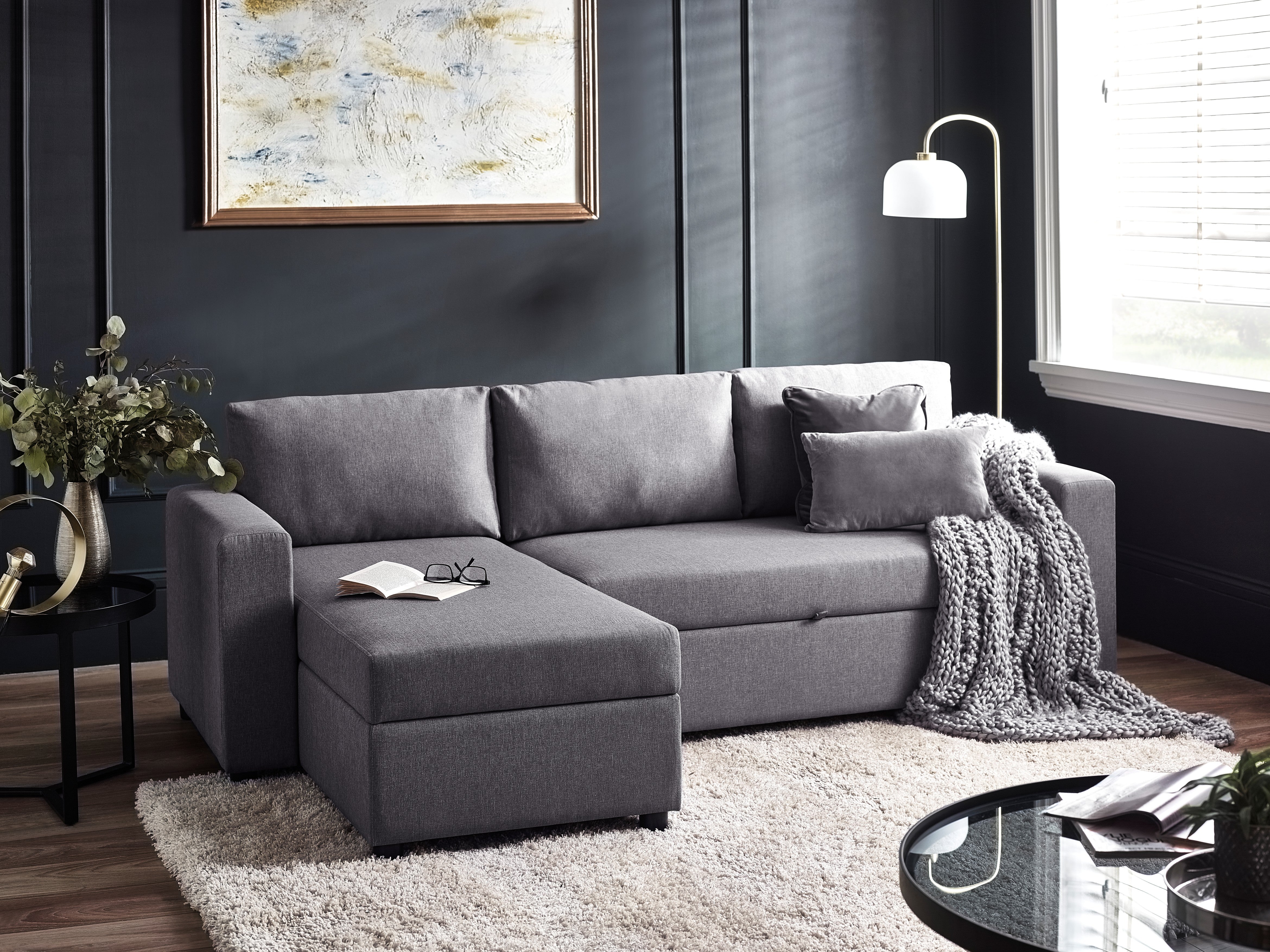 Gray sectional sofa in a living room with a rug, coffee table, and decorative elements.