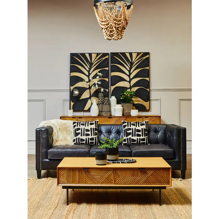 Living room with black leather sofa, wooden coffee table, and decorative wall art.
