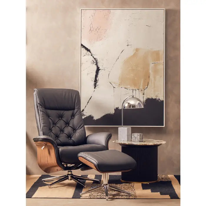 Black leather armchair with ottoman in a room with abstract art and side table.