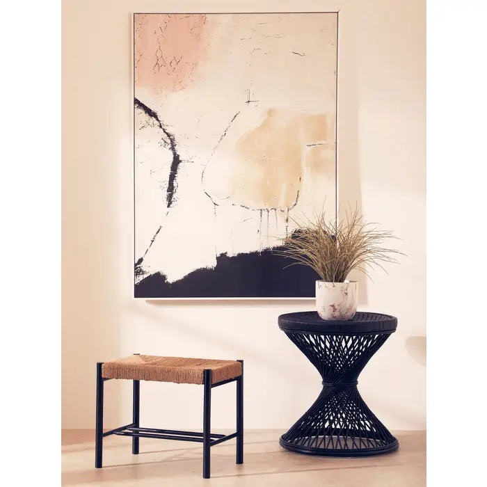 Decorative interior setting with abstract art, side table, and stool.