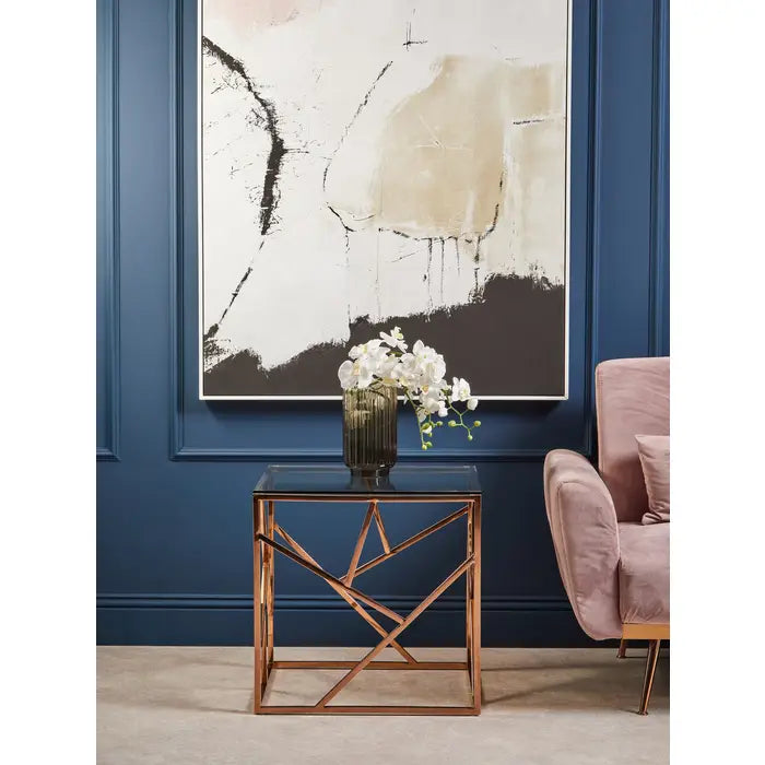 Modern interior with abstract art, glass table, and pink chair against a blue wall.