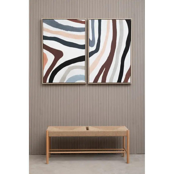 Two abstract wall art pieces above a wooden bench against a striped wall.