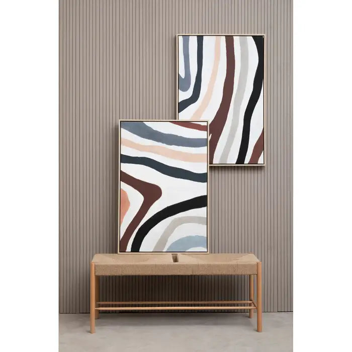 Two abstract wall art pieces on a wooden shelf against a striped wall.