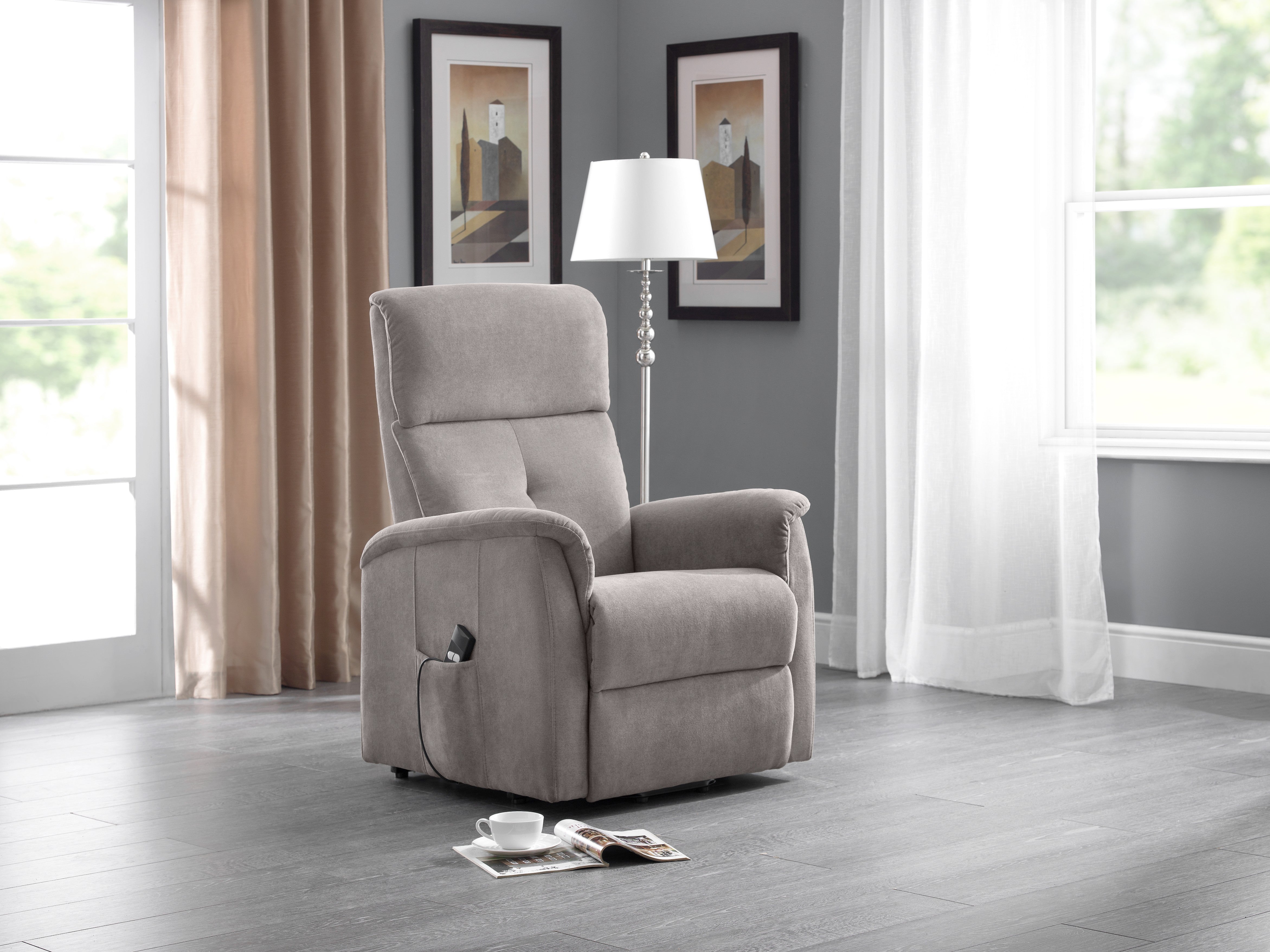 Gray recliner chair in a living room setting with a lamp and window.