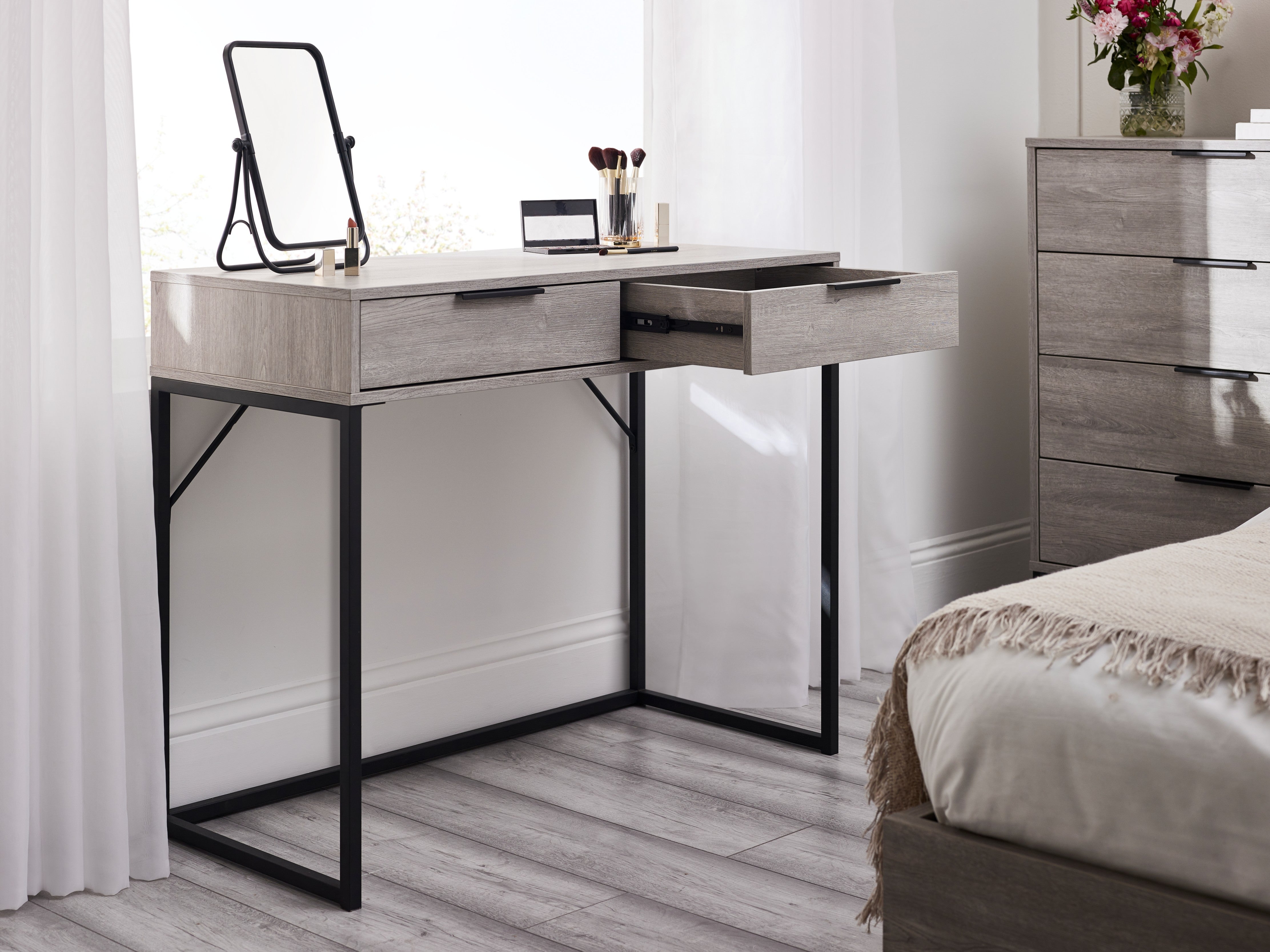 Modern bedroom with a desk, mirror, and dresser.
