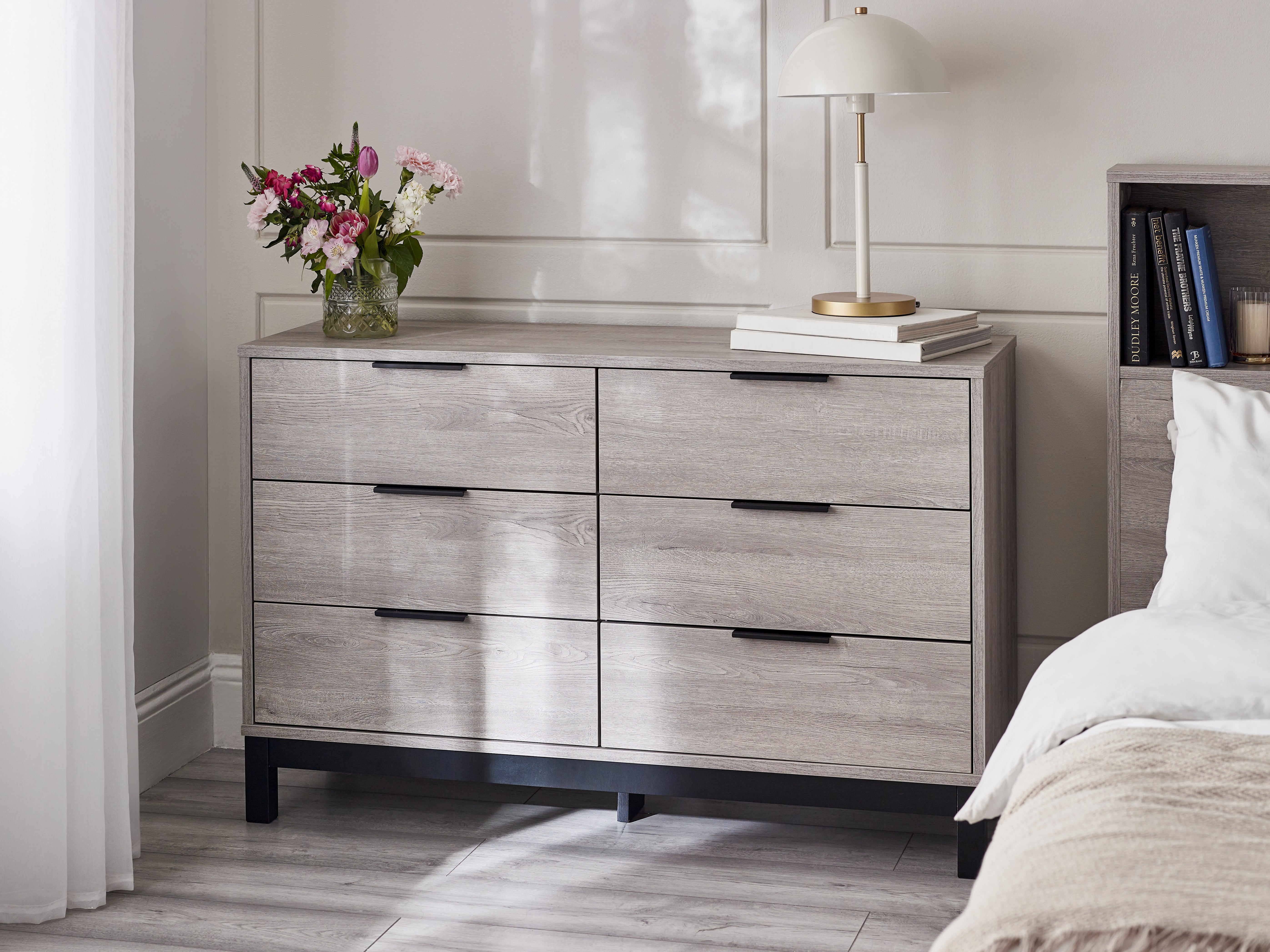 Wooden dresser with floral arrangement and books in a bedroom setting
