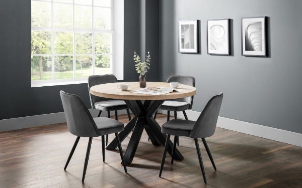Dining room with round table and gray chairs against a gray wall with framed pictures.
