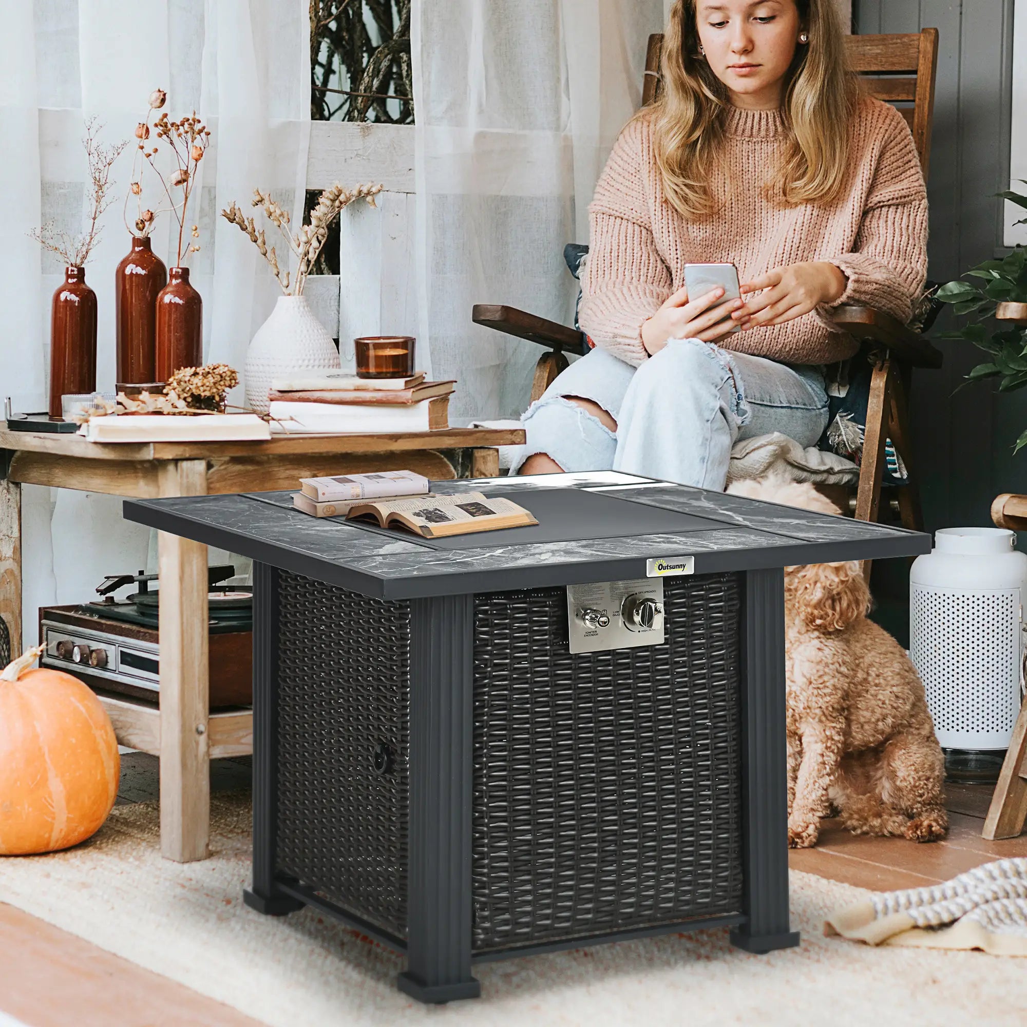 Woman sitting by a fire pit table in a cozy living room with a dog.