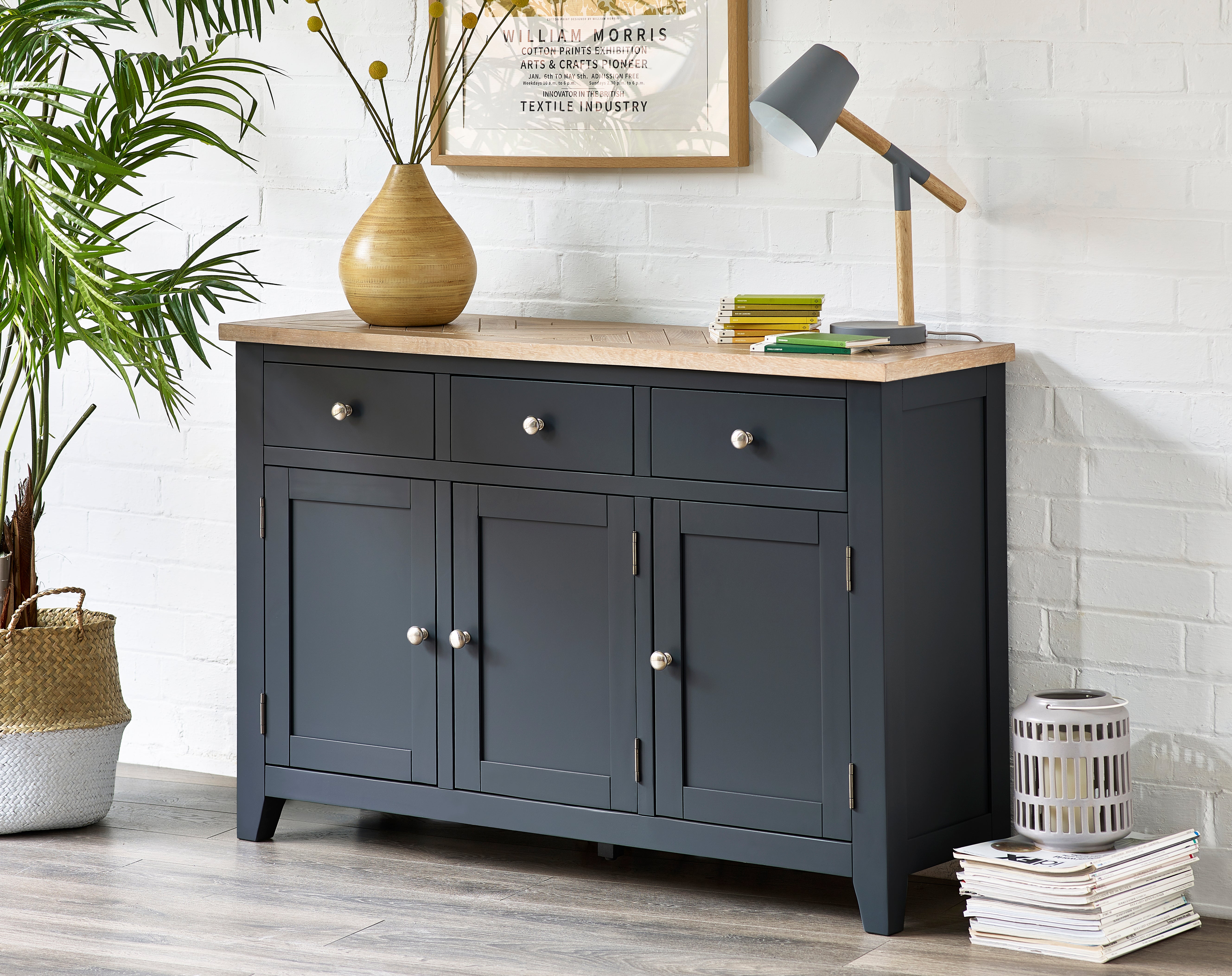 Dark grey sideboard with wooden top in a room with a plant and books.