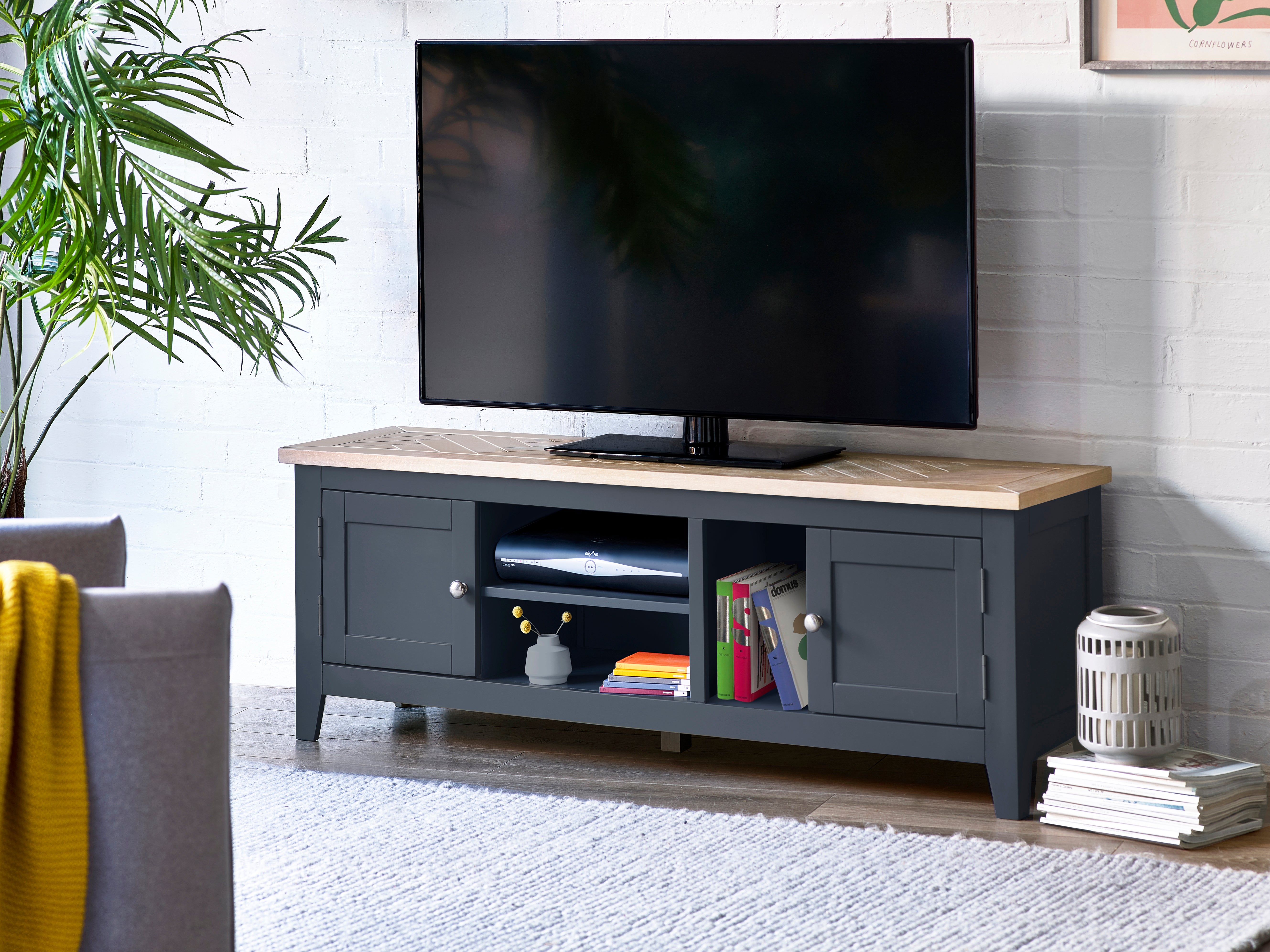 TV on a wooden stand in a living room with books and decor items.