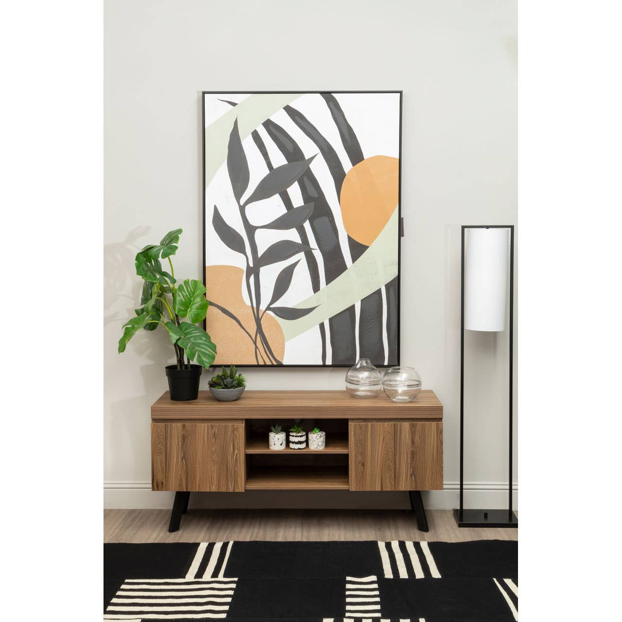 Modern living room with a wooden console table, abstract art, and decorative items.