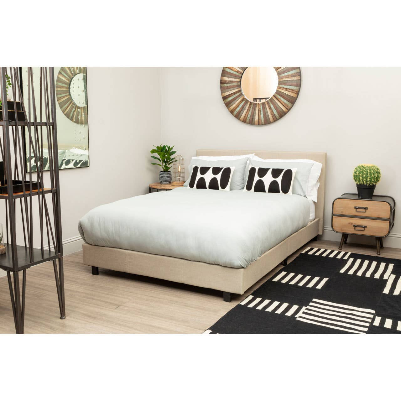 Beige bed in a bedroom with a black and white patterned rug