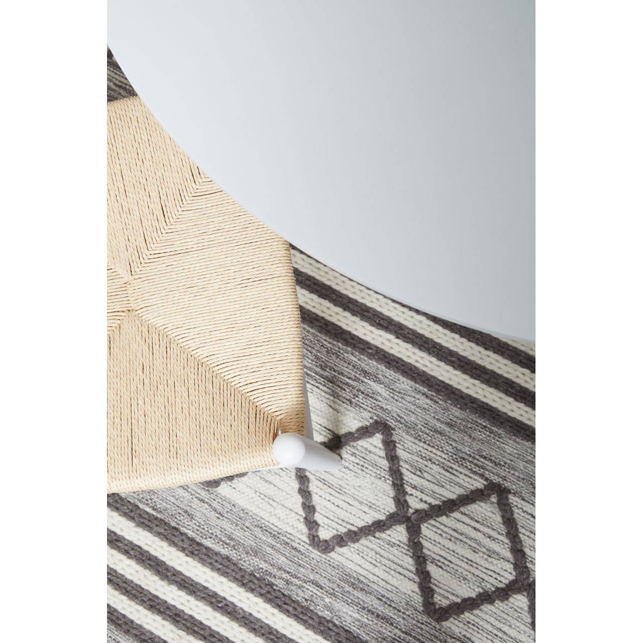 Close-up of a textured rug with geometric pattern on a light gray background