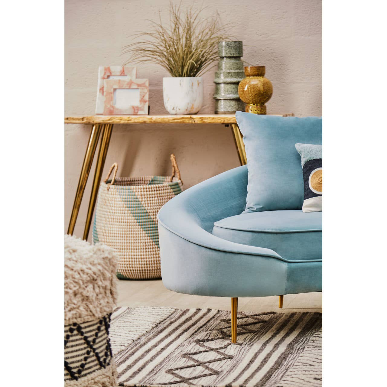 Light blue sofa in a living room with decorative items on a wooden shelf.