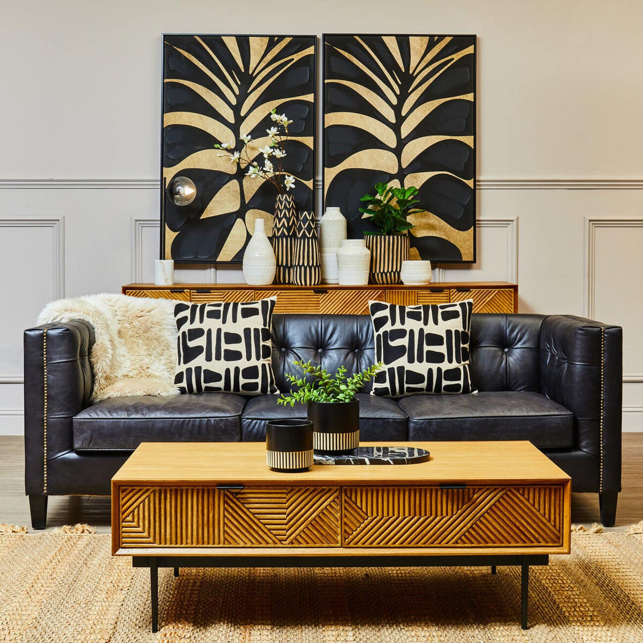 Living room with a black leather sofa, wooden coffee table, and decorative wall art.