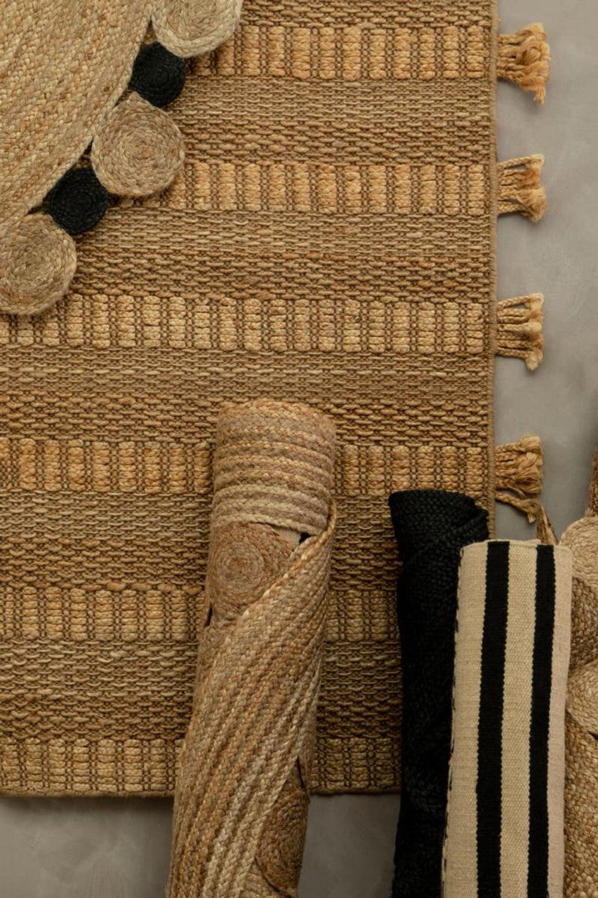 Close-up of textured rugs with pom-pom details on a neutral background