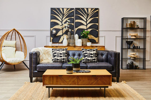 Modern living room with a black sofa, wooden coffee table, and decorative wall art.