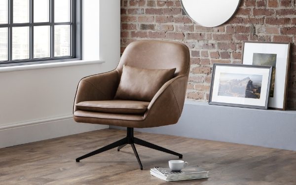 Brown armchair in a room with a brick wall and framed pictures.