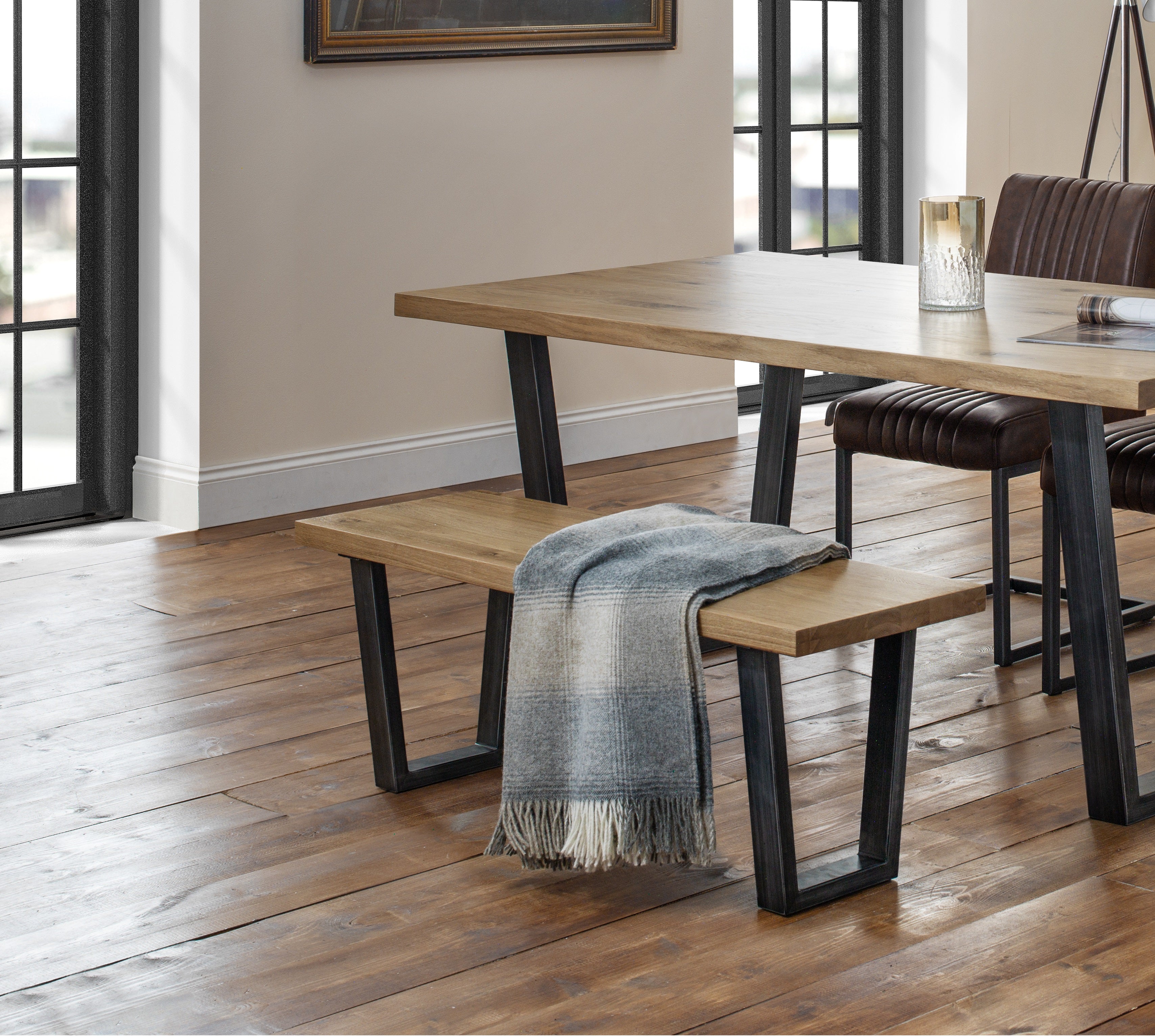 Dining area with wooden table, bench, and chairs on a wooden floor.