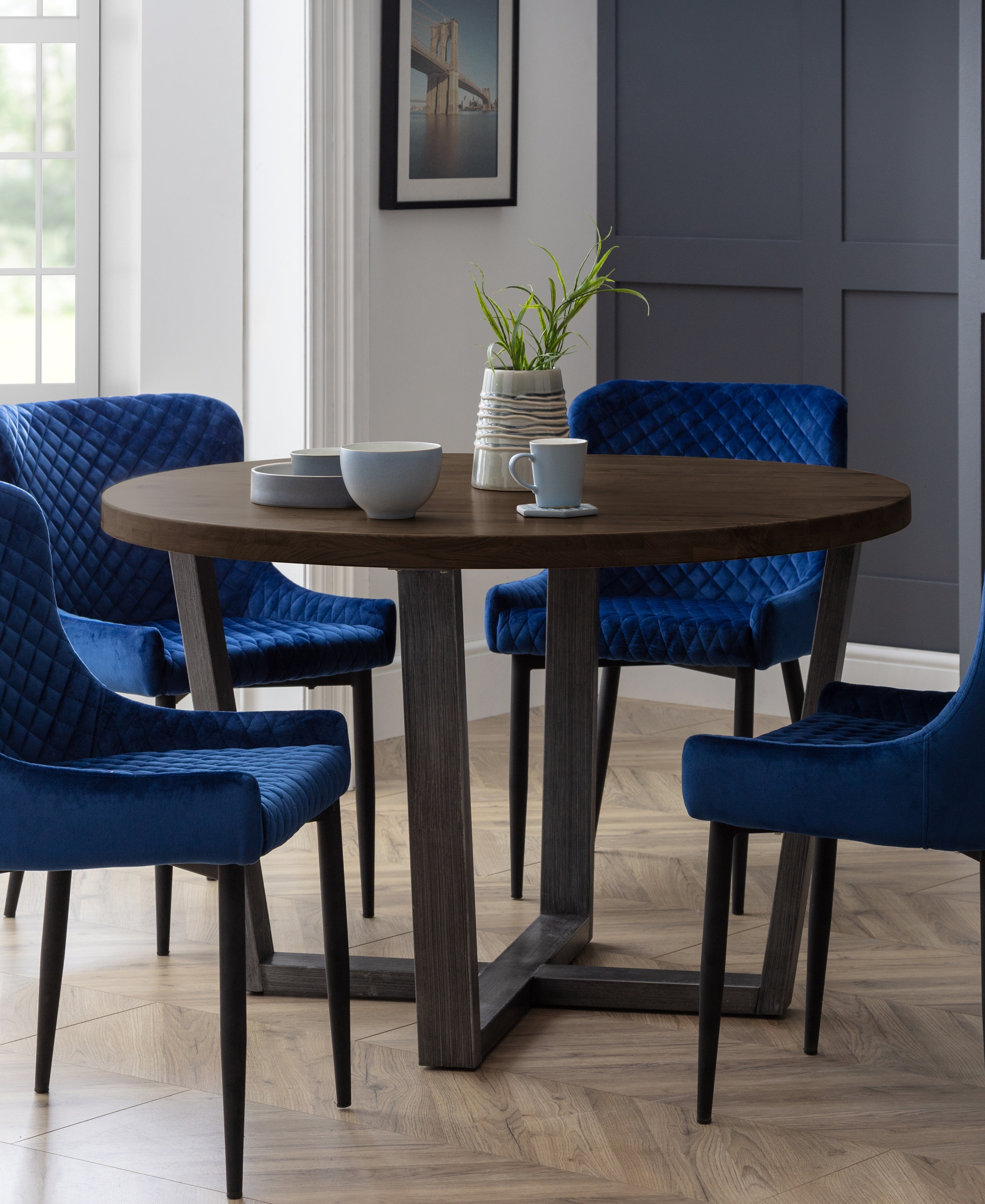 Dining room with a round wooden table and blue chairs.