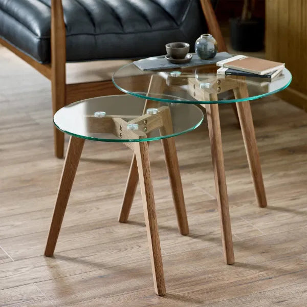 Two glass coffee tables with wooden legs on a wooden floor.