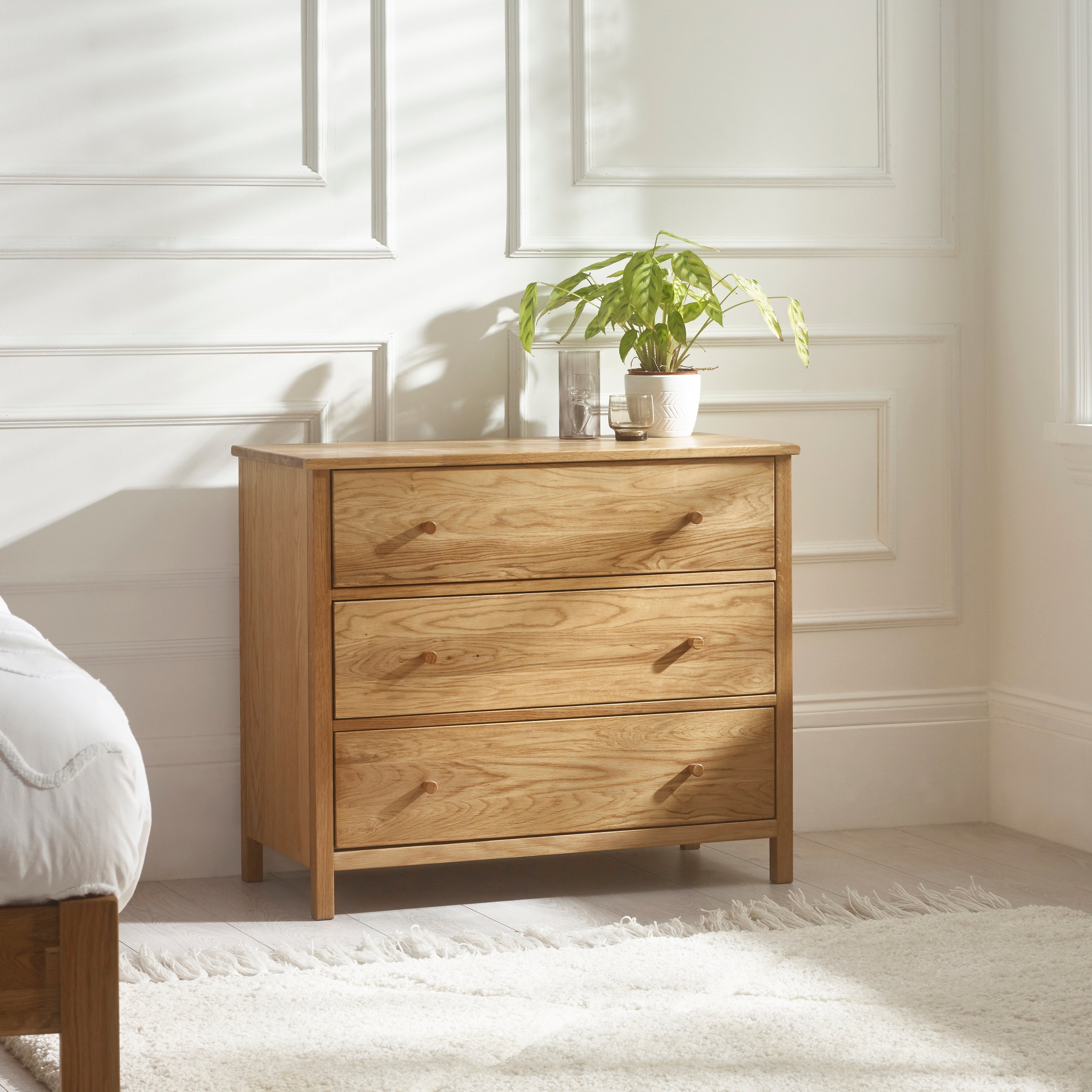 Wooden dresser with three drawers in a bedroom setting