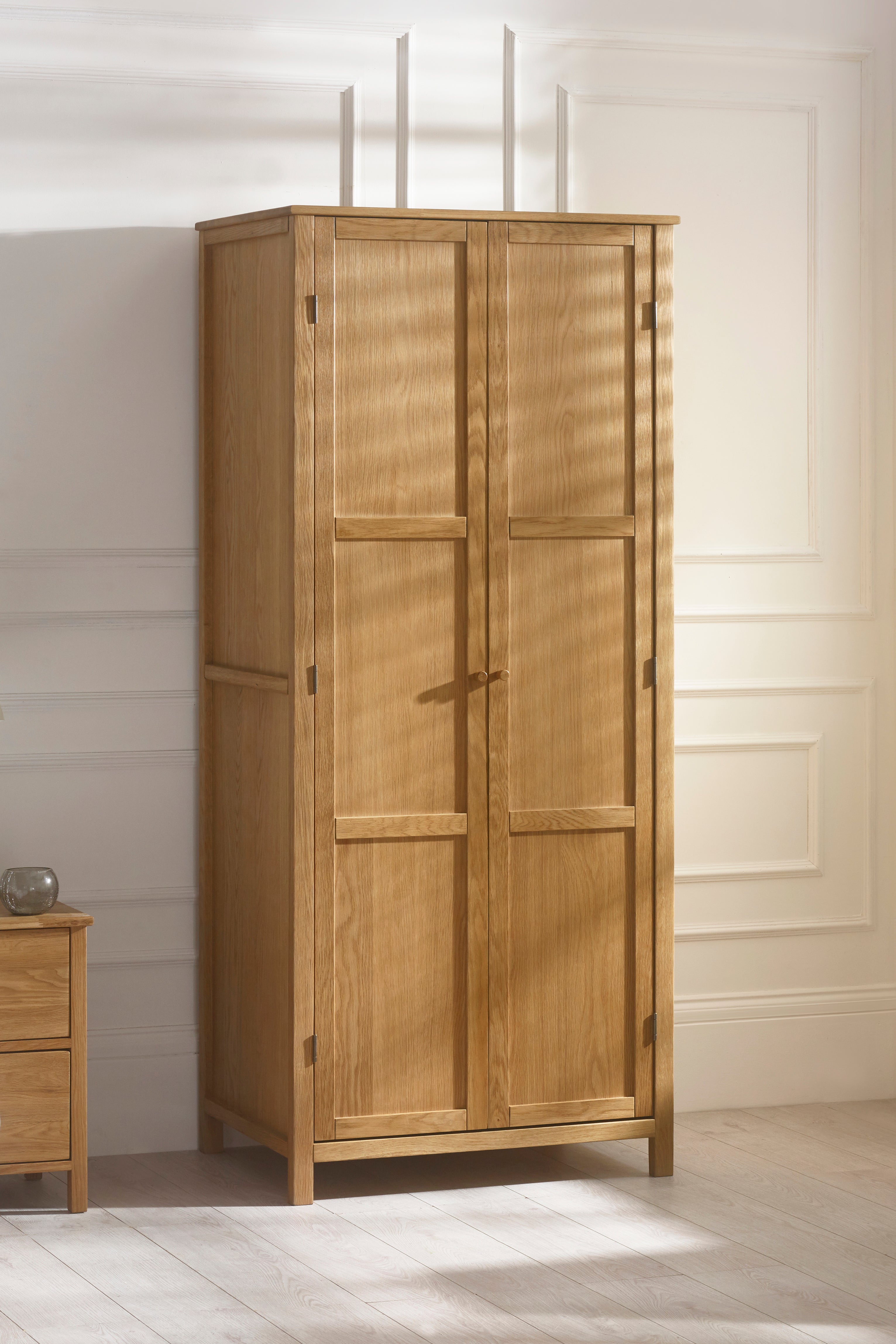 Wooden wardrobe with two doors in a room with light-colored walls and flooring.
