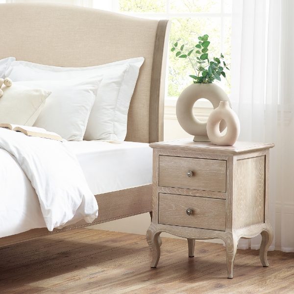 Bedroom with a wooden nightstand next to a bed with white bedding.