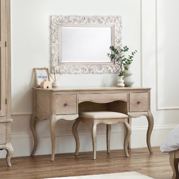 Wooden vanity with mirror and decorative items in a room.