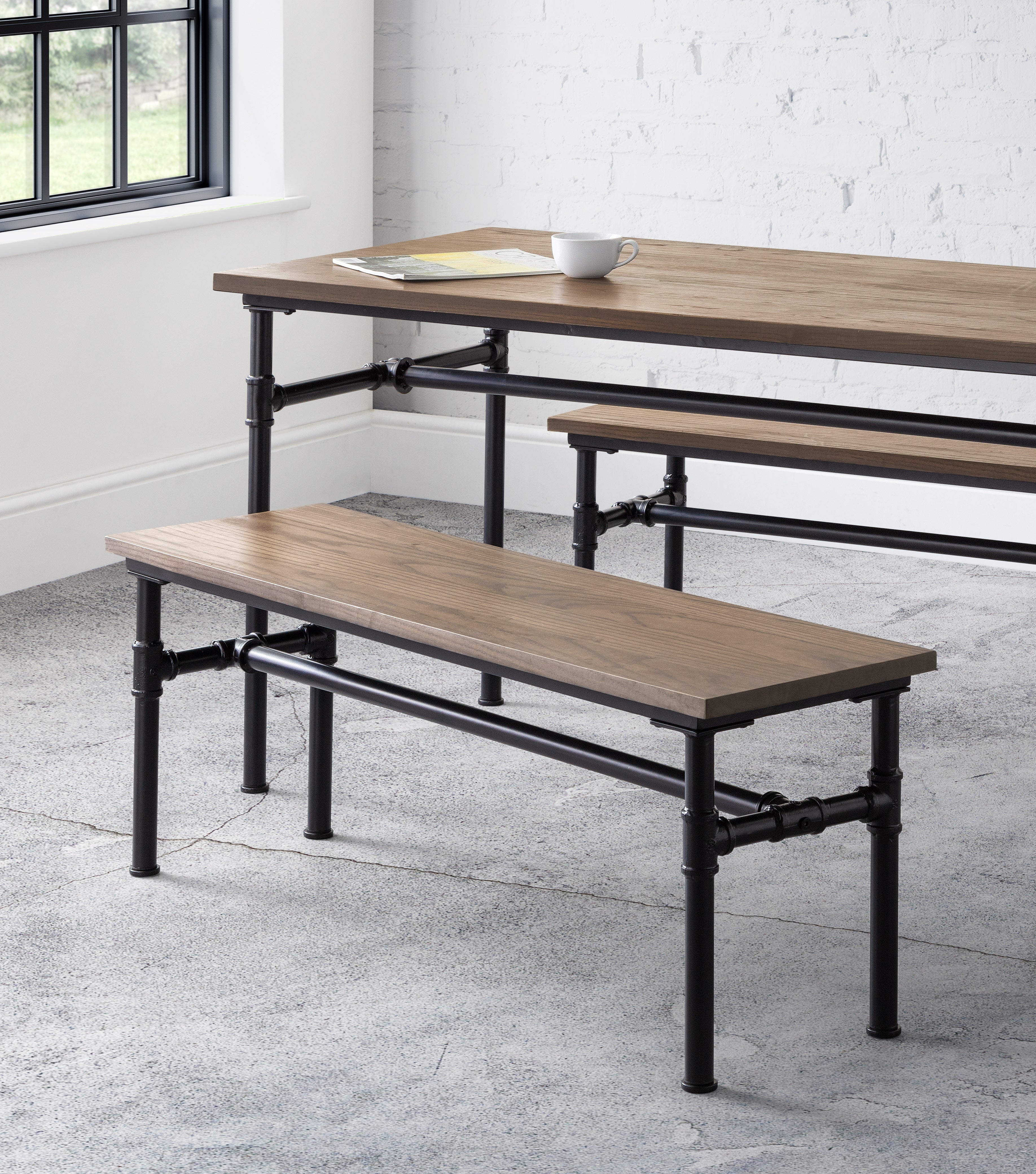 Wooden dining table and benches with black metal legs in a modern interior setting.