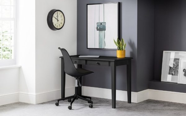 Black desk with chair in a room with a clock, plant, and framed pictures.