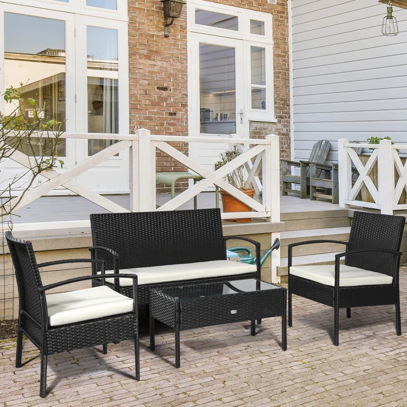Outdoor patio set with black wicker furniture and white cushions on a patio.
