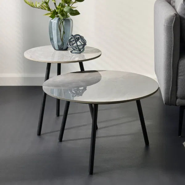 Two marble coffee tables with black legs in a living room setting.