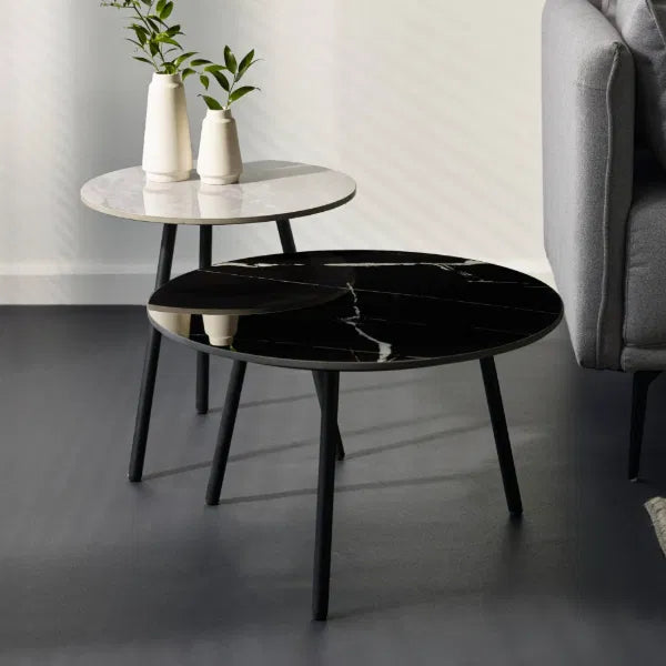 Two round marble tables, one black and one white, in a living room setting.