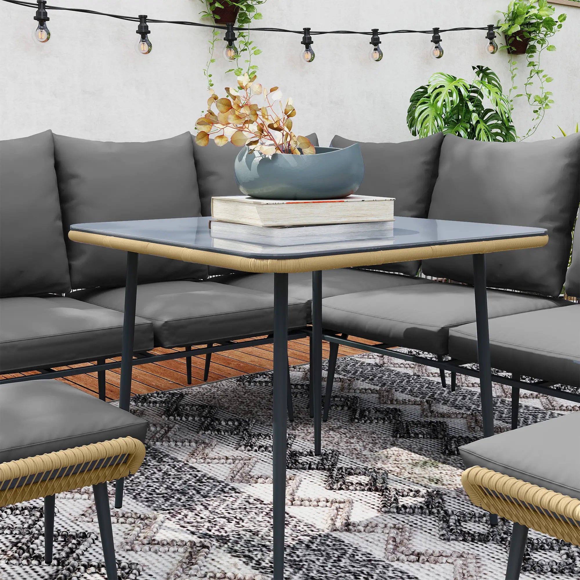 Outdoor seating area with gray cushions, a glass table, and decorative elements.