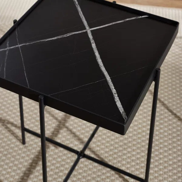 Black marble side table with geometric design on a textured floor