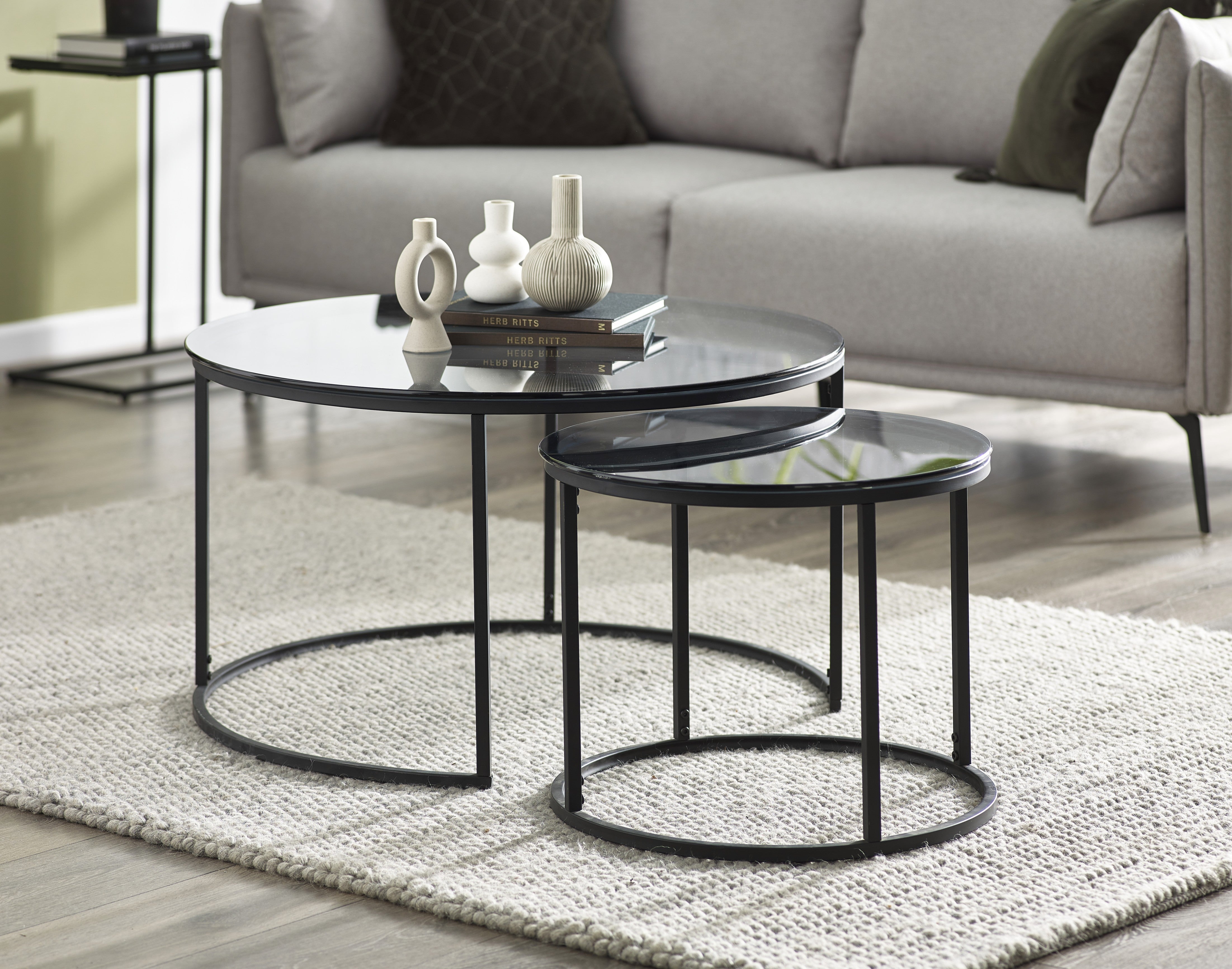 Set of three round coffee tables with black metal bases in a living room setting.
