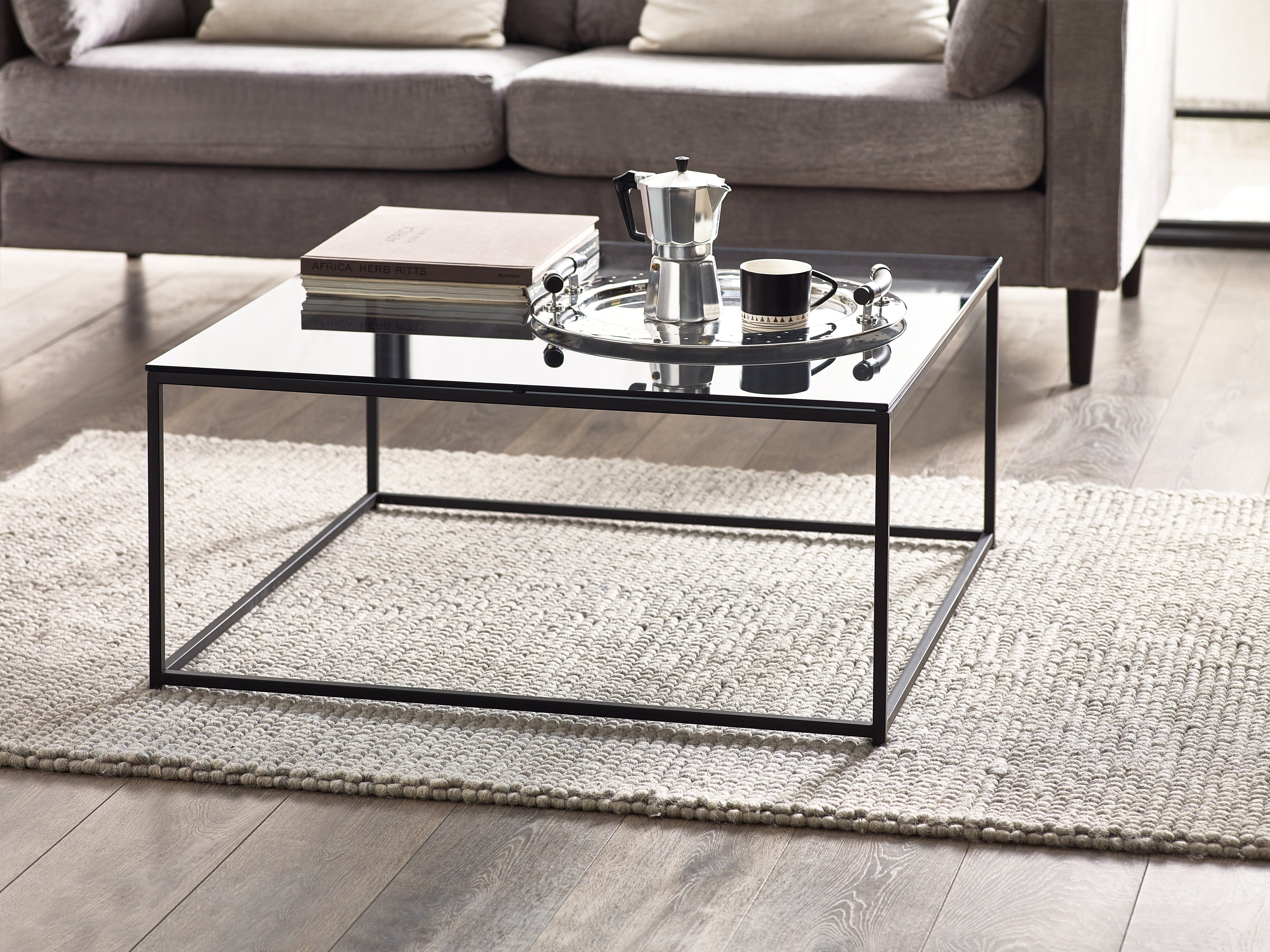 Glass coffee table with a black metal frame in a living room setting.